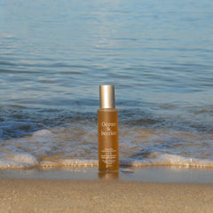 Skincare bottle on a beach with ocean and ships in the background