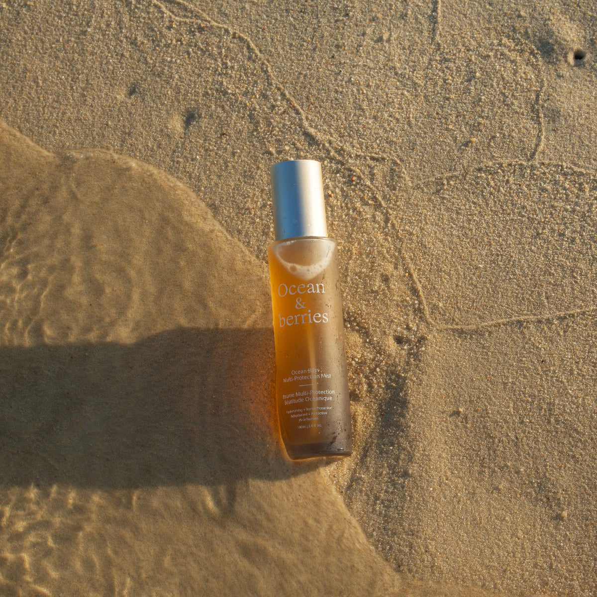 Skincare glass bottle on wet sand
