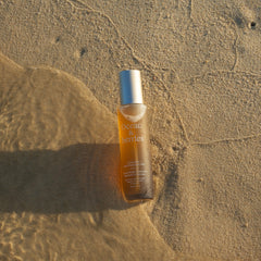 Skincare glass bottle on wet sand