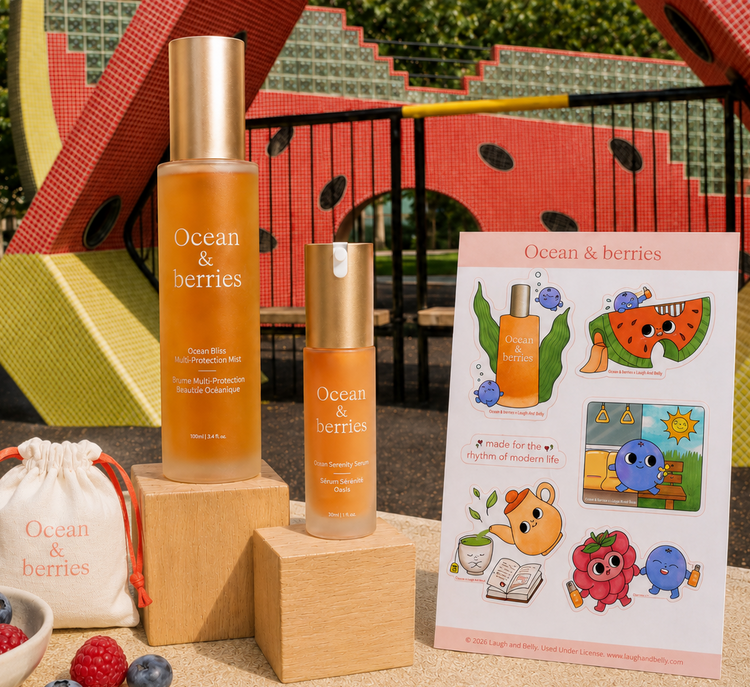 Ocean & berries skincare set displayed outdoors on a table, including a tall and short amber bottle with gold caps, a branded drawstring pouch, a bowl of fresh berries, and a colorful printed card, set against a playground background.
